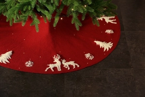 Detail of red knit Christmas tree skirt featuring white reindeer and snowflake embroidery