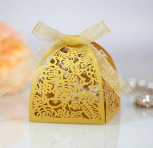 Close-up of golden laser-cut wedding favor box with intricate floral patterns and ribbon