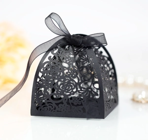 Macro detail of laser-cut black paper wedding candy box with intricate rose patterns