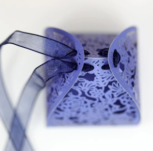 Macro detail of laser-cut floral paper candy box with elegant blue ribbon closure