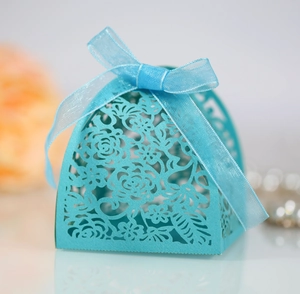 Close-up of a laser-cut wedding candy box in cyan paper with a matching silk ribbon bow