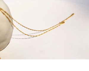 Detail shot of a minimalist gold crescent moon necklace on a wavy Singapore chain