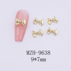 Detailed macro view of 9x7mm gold bow nail charms showing dimensions and 3D fit on pink nail