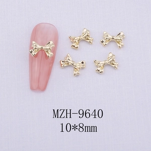 Detail of gold metal bow nail art charm MZH-9640 size 10x8mm on pink manicure