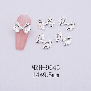 Macro shot of silver metal bow nail charms with 14x9.5mm dimensions for DIY nail art