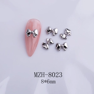 Detail of silver alloy bow nail charm MZH-8023 8x6mm on pink manicure with metallic luster