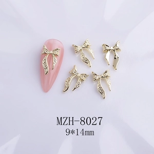 Detailed macro view of 9x14mm golden bow nail charms with glitter and rhinestones