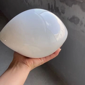 Close-up of a glossy white egg-shaped ceramic ornament held by a hand for home decoration