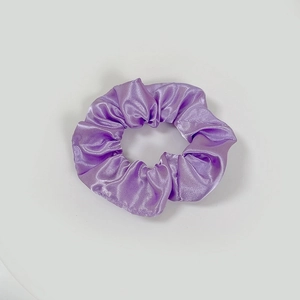 Macro view of lavender satin scrunchie showing glossy silk texture and pleated design