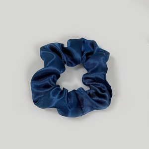 Detailed view of navy blue satin scrunchie showing smooth silk texture and ruched design