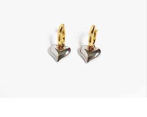 Macro shot of two-tone gold and silver heart drop earrings on a white background