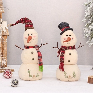 Pair of festive snowman plush ornaments with knit hats and scarves in a cozy Christmas setting