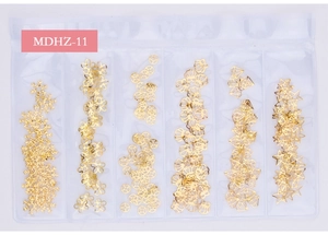 Detailed view of six gold metallic nail art charms including snowflakes and shells