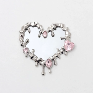 Detail of silver liquid metal heart mirror with pink rhinestone accents and y2k style