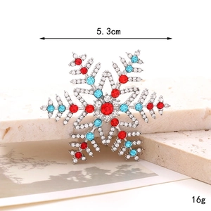 Detail of snowflake brooch with red and blue rhinestones on stone background