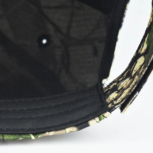 Détail de la bordure noire cousue et de la texture en toile camouflage sur la casquette