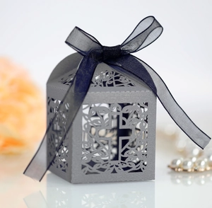 Detail of laser-cut cross favor box in pearl paper with navy blue chiffon ribbon bow