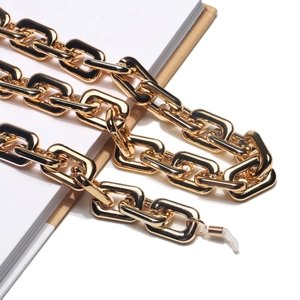 Close-up of thick gold metal glasses chain with silicone hooks on a vintage book