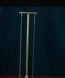 Close-up of elegant gold necklace on T-bar stand against deep blue velvet background