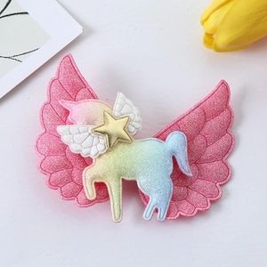 Close-up of rainbow unicorn hair clip with pink glitter wings and gold star detail