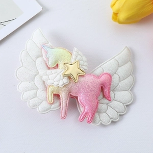 Macro detail of rainbow unicorn hair clip with glitter sequins and white angel wings