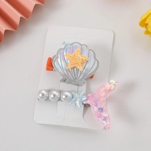 Detail of shell and mermaid tail hair clips with pearls and starfishes on card