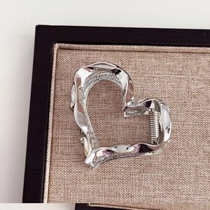 Detail view of a silver heart-shaped metal hair claw clip with high-shine plating