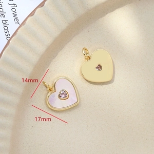 Macro view of gold-plated heart charms with mother of pearl and pink crystals, 14mm size