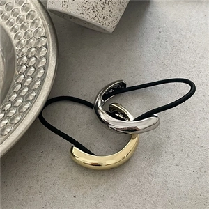 Detail of mirror-finish gold and silver half-round ponytail cuffs with black elastic bands