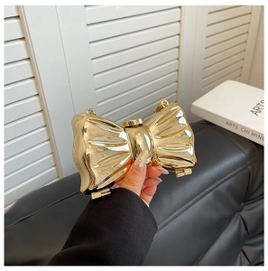 Close-up of golden bow-shaped metal evening clutch bag with a delicate chain strap