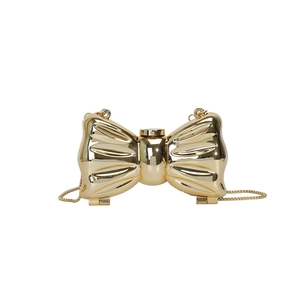 Golden bow-shaped acrylic evening clutch bag with metal chain strap on white background