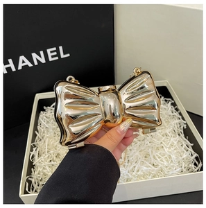 Macro view of golden bow evening bag with metallic folds and elegant chain strap