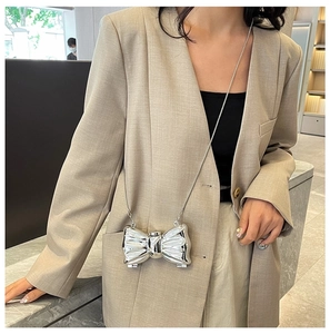 Close-up of a silver metal bow evening bag with a sleek chain strap on a blazer