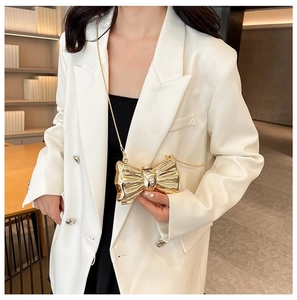 Detail of a gold metallic bow-shaped evening clutch bag with an elegant chain strap