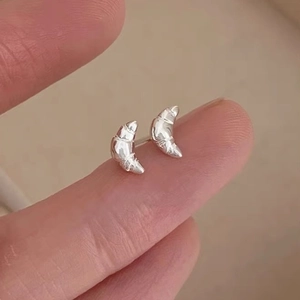 925 Sterling silver croissant stud earrings in polished silver on a fingertip