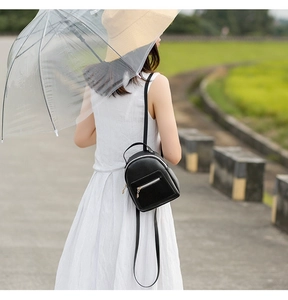 Detail of black mini PU leather backpack featuring multi-pocket design and metal zippers