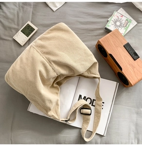 Flat lay of beige corduroy crossbody bag with adjustable strap on a lifestyle magazine
