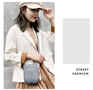 Detail of grey nylon crossbody bag with multi-layer zippers and adjustable strap