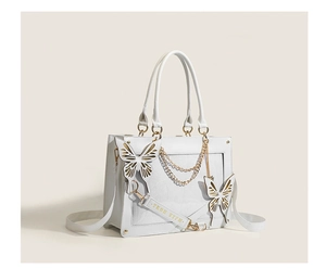 Detail of white butterfly tote bag featuring gold chains and geometric textures