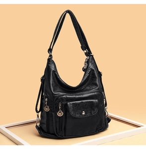 Detail view of black soft leather crossbody bag with multiple pockets and silver zippers