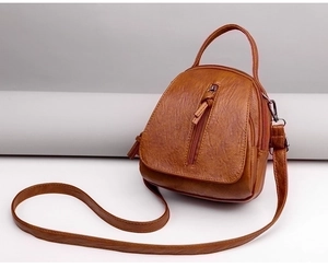Detail of vintage brown pebble faux leather crossbody bag with tassel and zipper