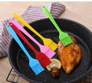 Silicone oil brushes in five colors shown on a skillet with grilled chicken breast