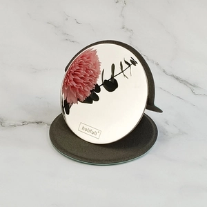 Portable round folding makeup mirror with gray matte base on white marble background