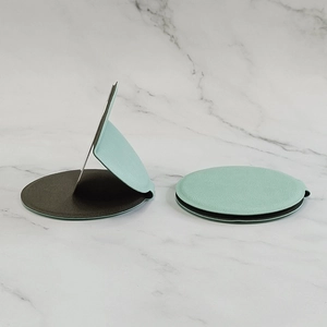 Portable mint green round leather folding mirror on a white marble surface