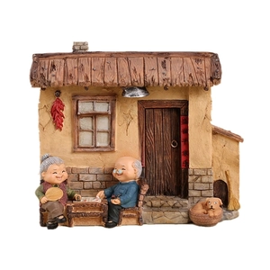 Miniature old couple elderly grandparents figurine sitting in front of a rural house