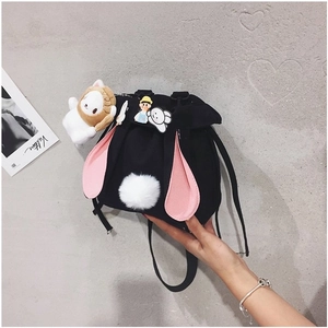 Detail view of a black canvas bucket bag featuring cute bunny ears and a plush pompom