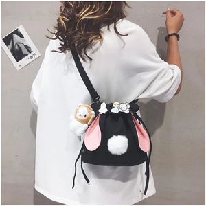 Detail of black canvas bucket bag featuring pink rabbit ears and cute cartoon pins