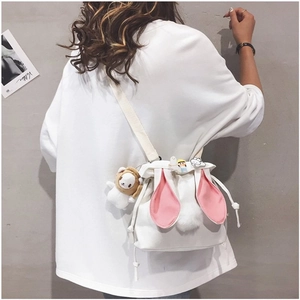 Detail of white canvas bucket bag featuring cute rabbit ears and plush lion charm