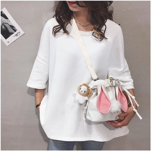 Close-up of white canvas bucket bag featuring cute rabbit ears and decorative badges