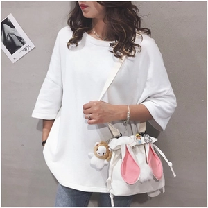 Detail view of canvas bucket bag with rabbit ears, plush charm and decorative pins